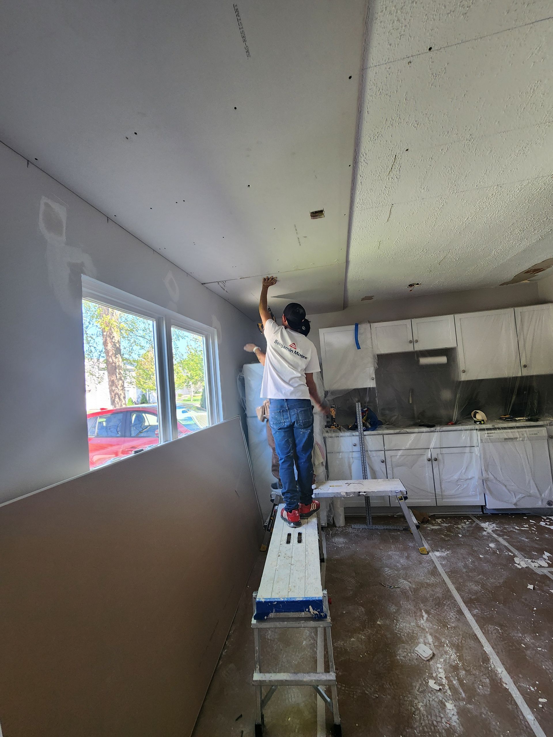 A man is standing on a ladder in a kitchen.