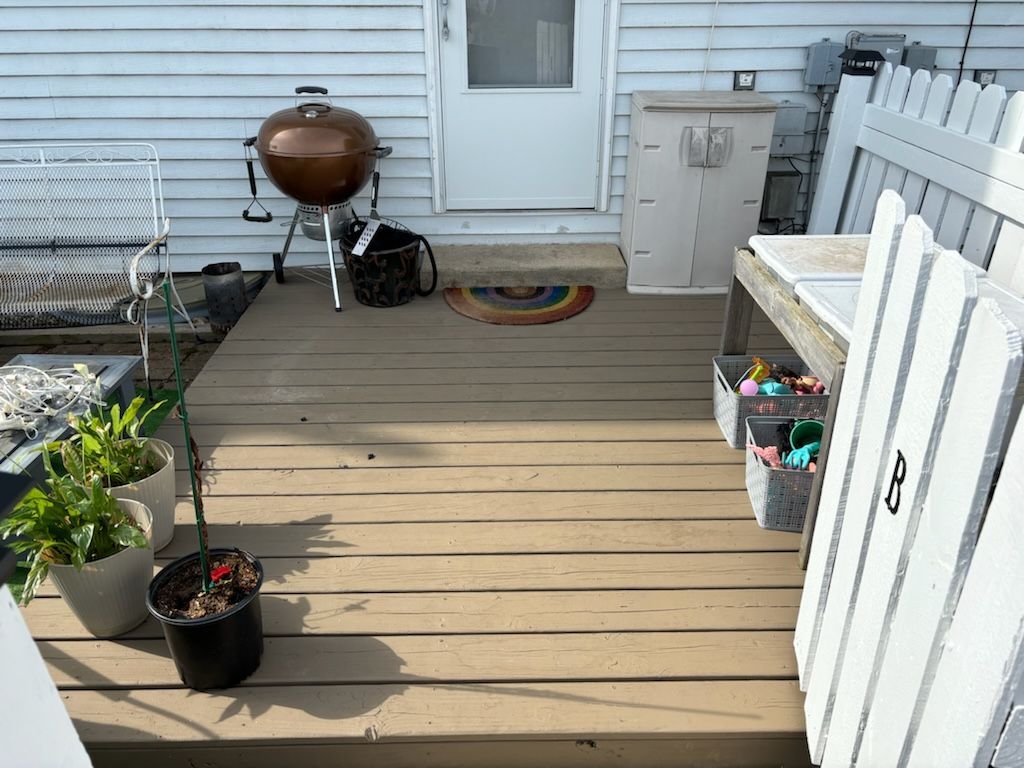 A wooden deck with potted plants and a grill on it.