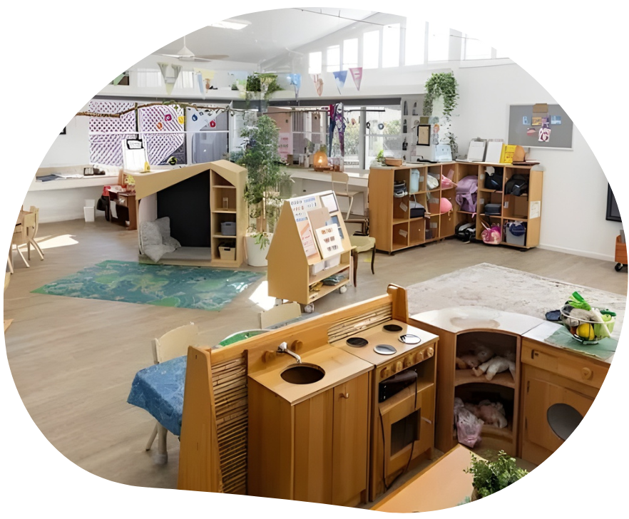 Interior of a bright, well-lit preschool classroom with various wooden play structures and educational materials.