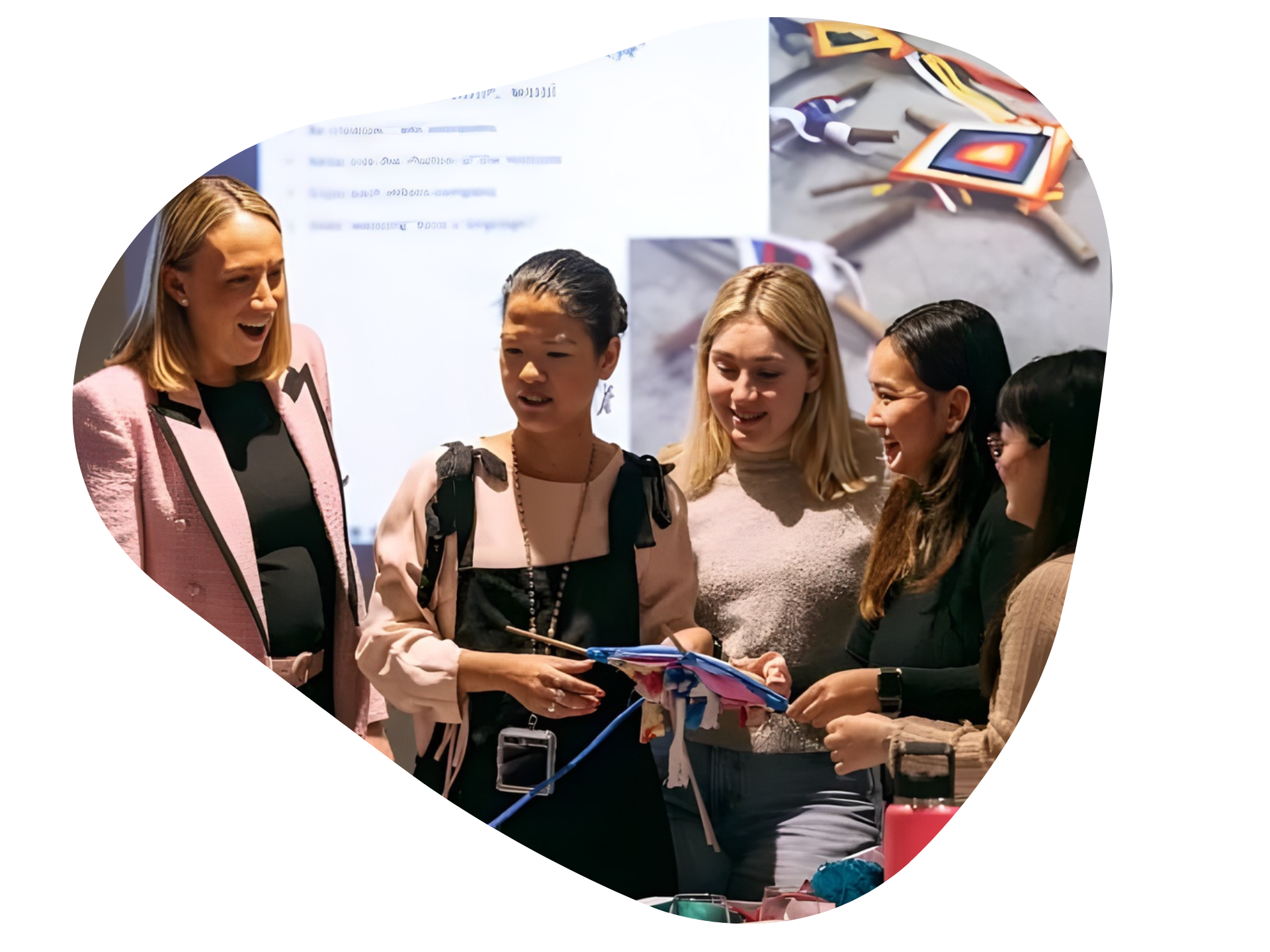 Group of people examining craft, one holding item, in front of a screen.