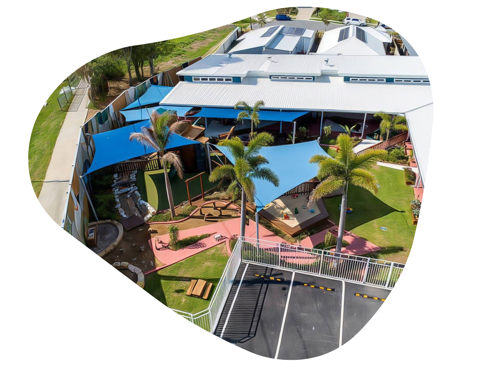 Aerial view of a childcare center with shaded outdoor play areas, green lawns, and parking lot.
