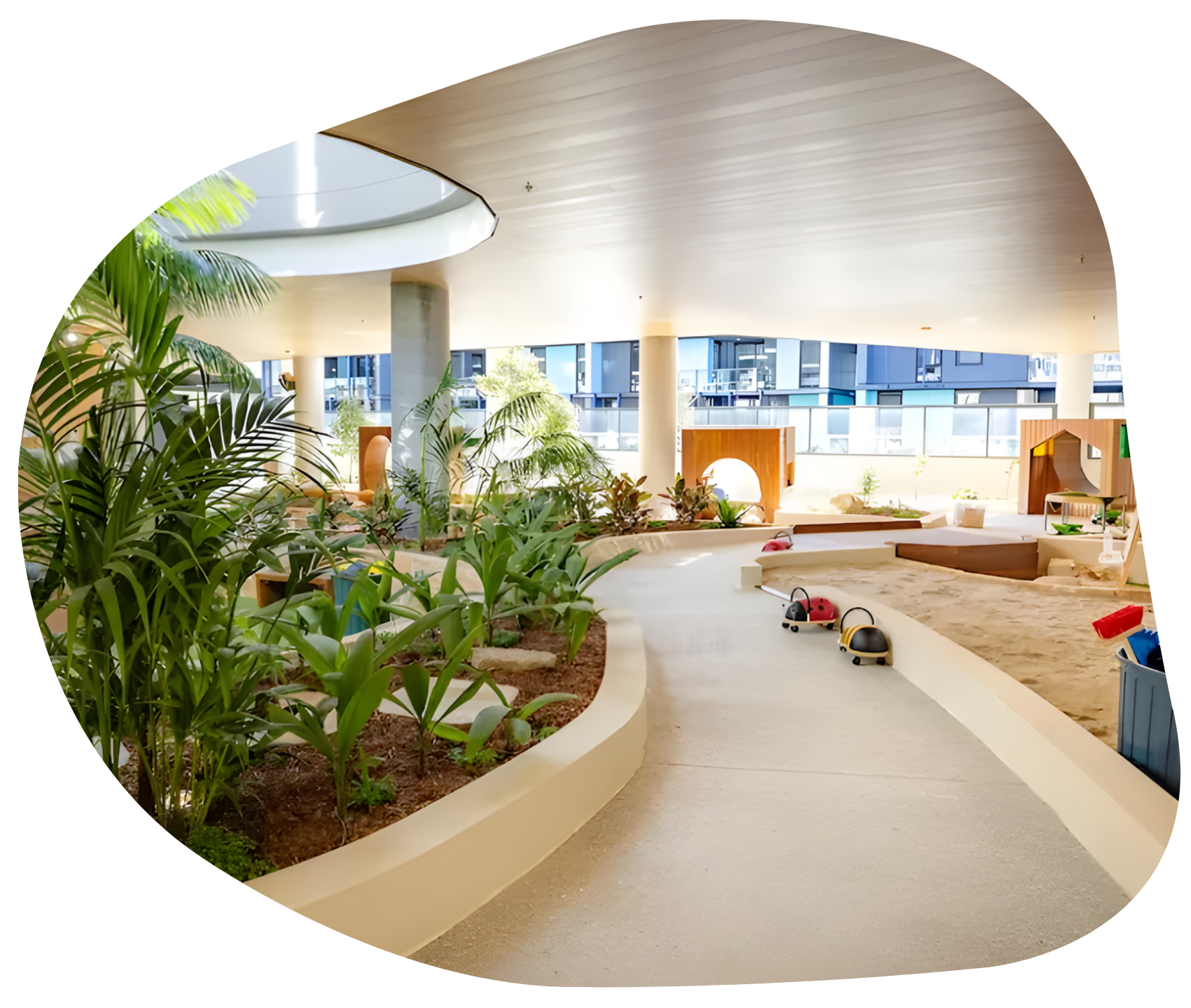 Indoor playground with sand pit, plants, and small toy vehicles.