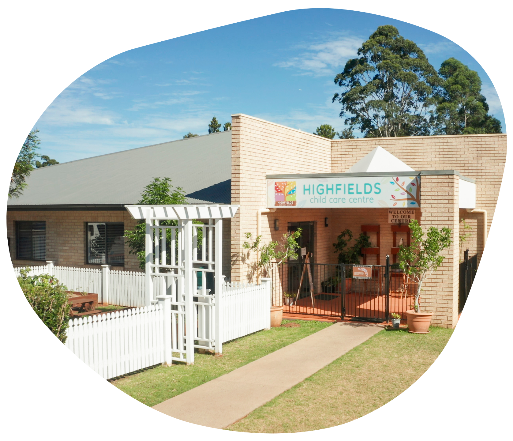 Highfields Early Learning center, a brick building with sign, white fence, and blue sky.