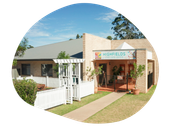 Highfields Early Learning Centre exterior, tan brick building, white picket fence, blue sky.