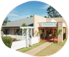 Highfields Early Learning Center, tan brick building with white picket fence, a garden, and blue sky.