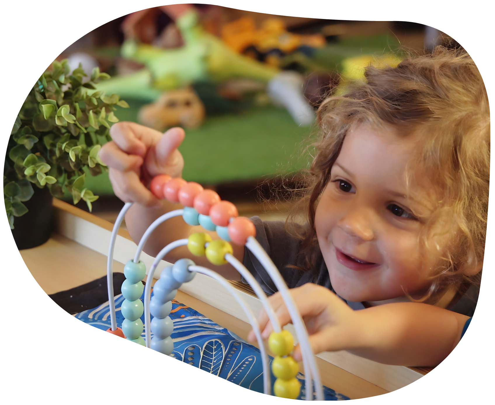 Child smiling while playing with a colorful bead maze.