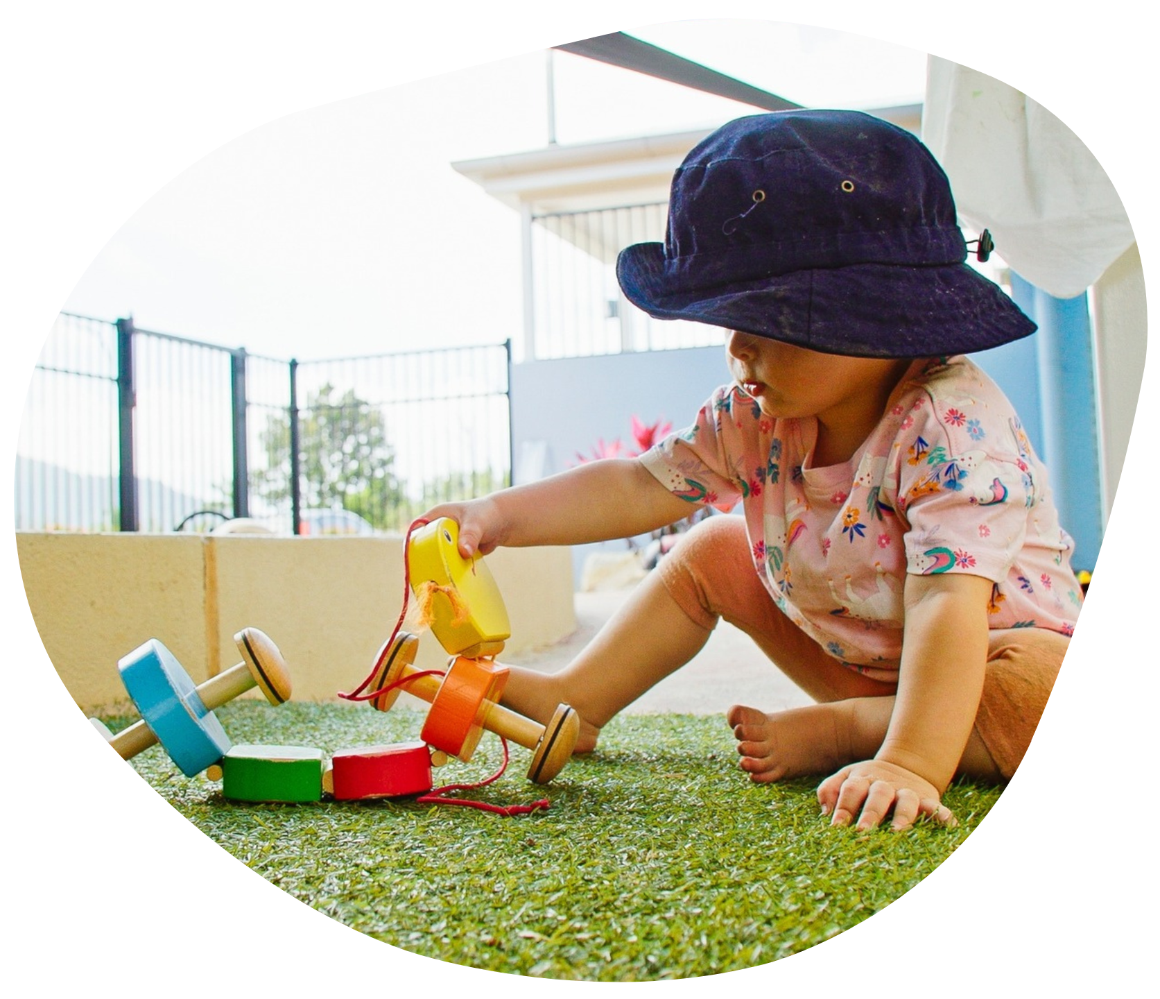 Child playing with colorful wooden toy on artificial grass.
