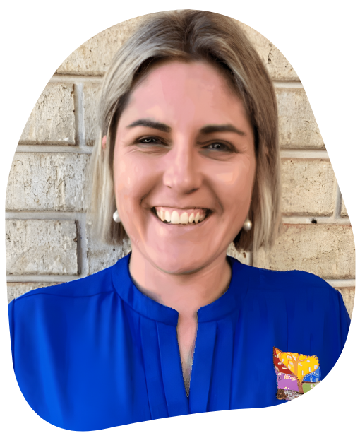 Woman with blonde hair smiling, wearing a blue shirt, in front of a brick wall.