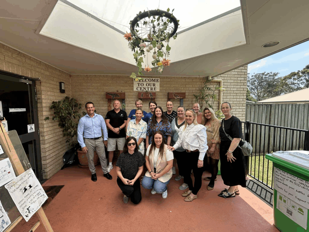 Group of people posing outdoors on a porch with signs and decorations.