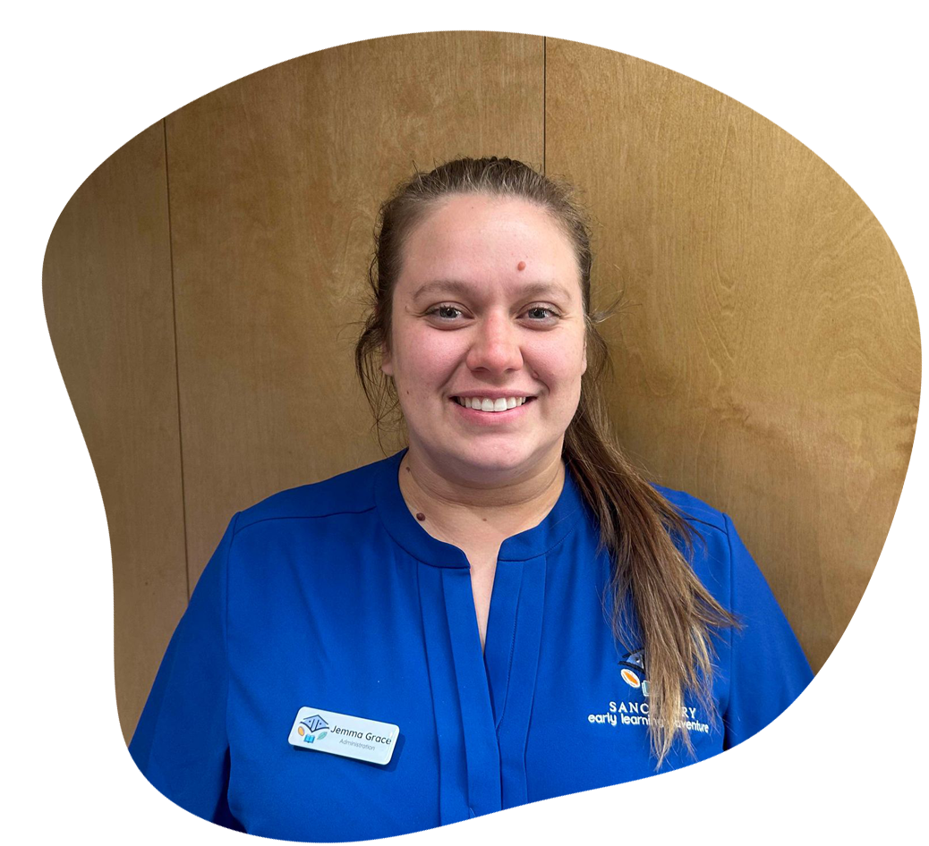 Woman in blue shirt smiles, name tag visible. Wooden panel background.