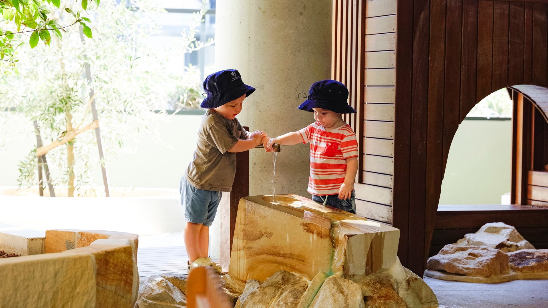 two children play outside with outdoor water feature