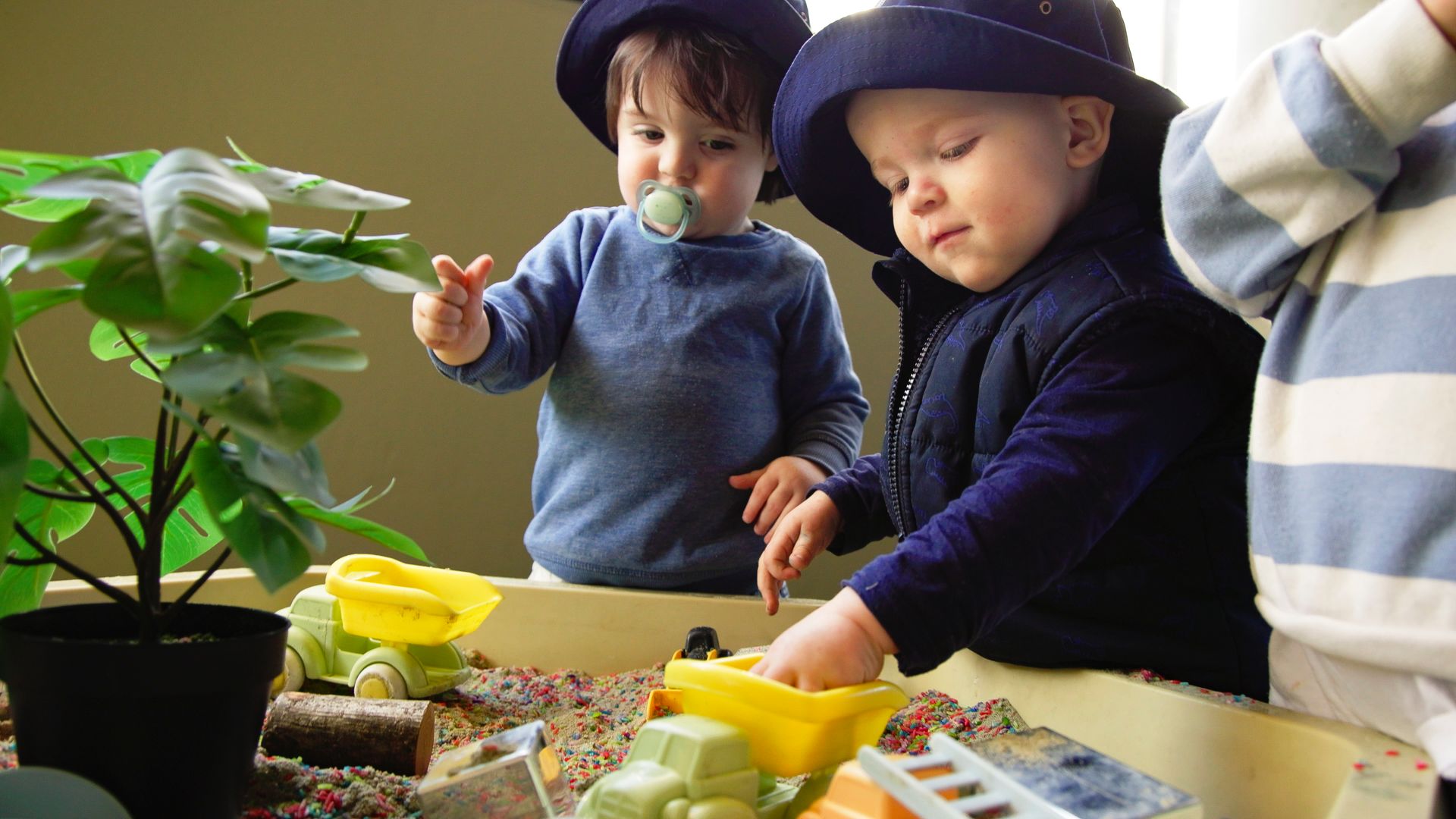 Two children playing with trucks and coloured rice