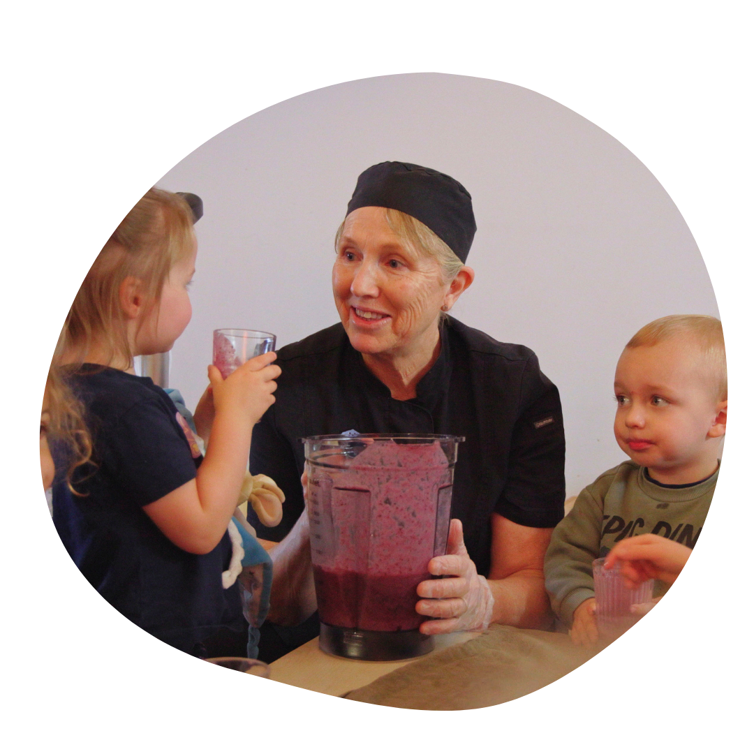 Chef making smoothie with two children who are drinking the smoothie. 