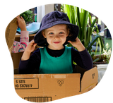 Hands with white paint, turning a wooden drill in sand.