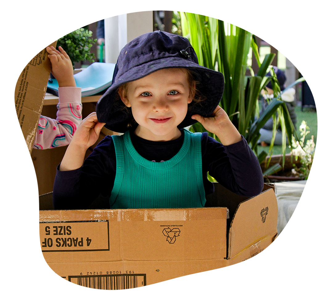Hands with white paint, turning a wooden drill in sand.