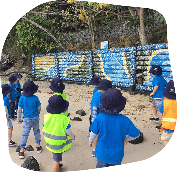 Children and adults with hands on a large, round drum.