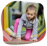 Girl crawling through a colorful tunnel at a playground.