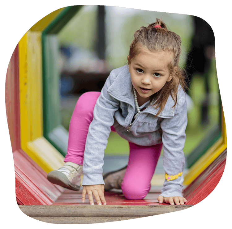 Girl crawling through a colorful tunnel at a playground.