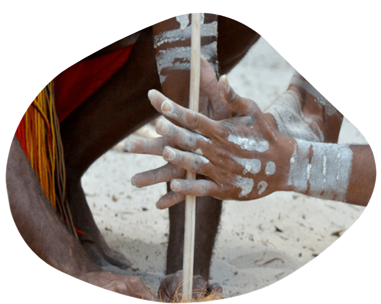 Hands with white paint, turning a wooden drill in sand.