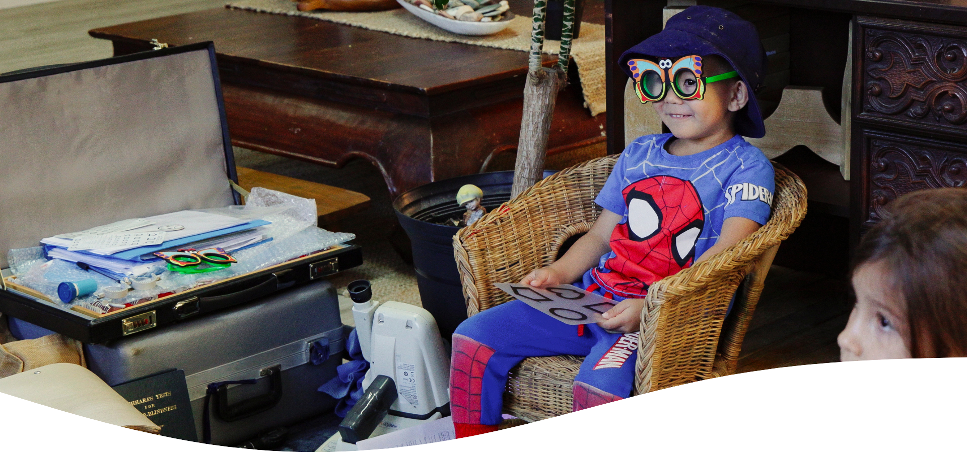 Group of young children sitting outdoors wearing hats and smiling.