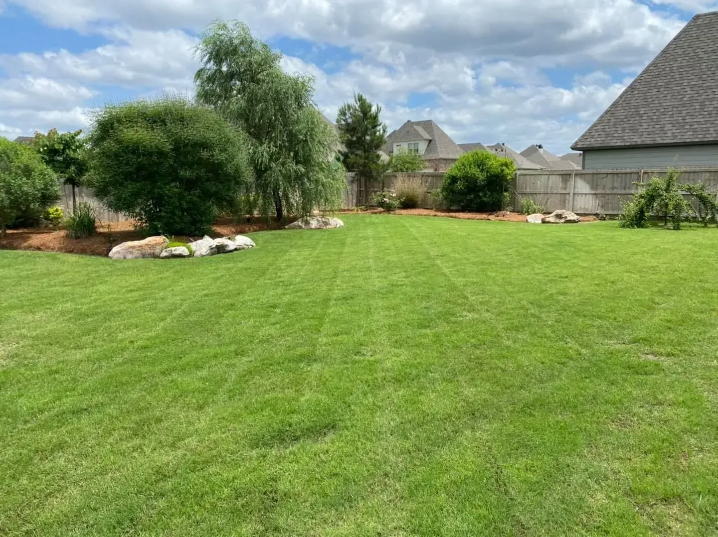 A freshly mowed lawn in front of a brick house.
