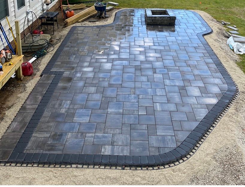 Finished brick patio with dark border, square pavers, and fire pit.