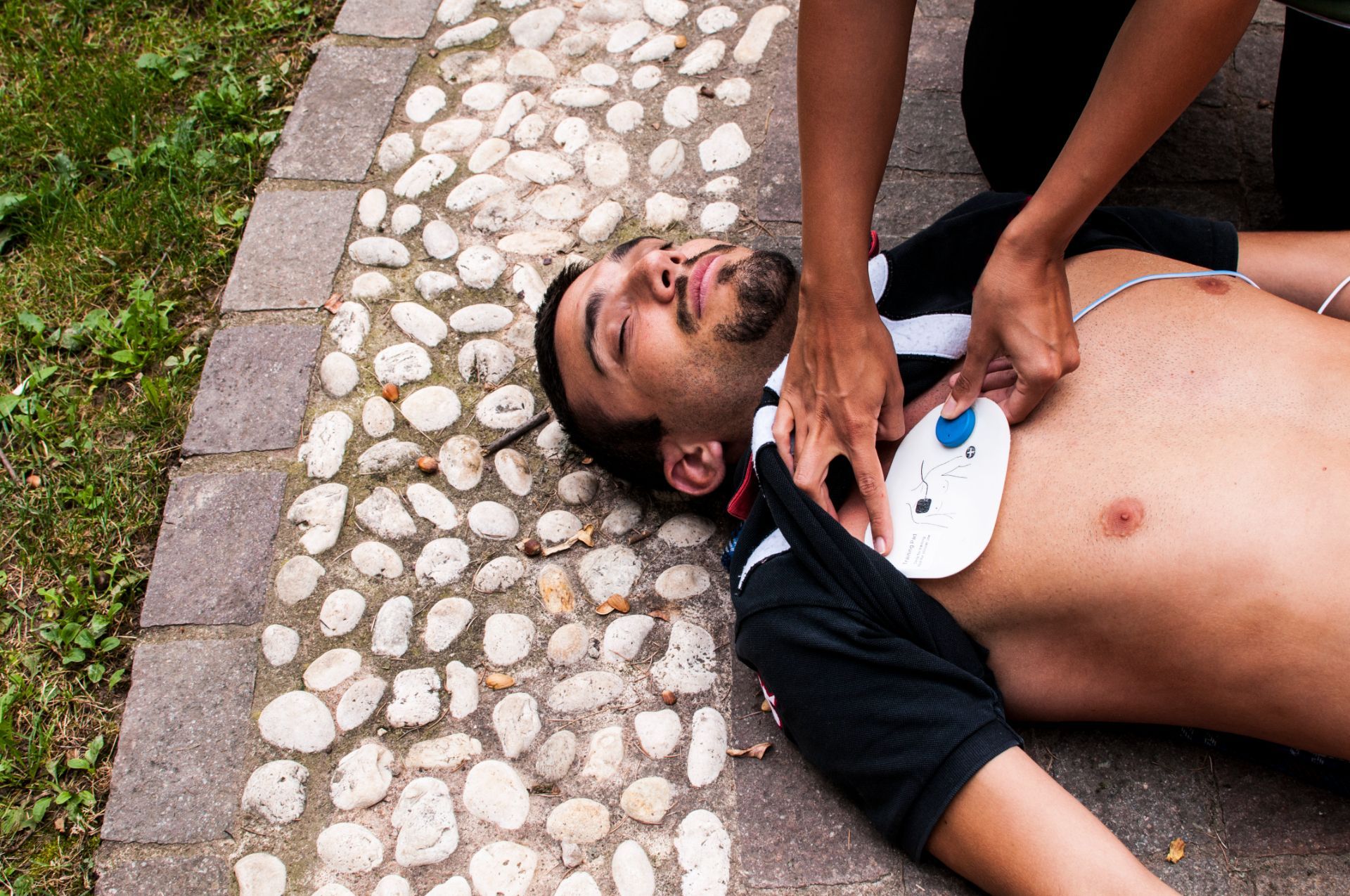 A man is laying on the ground with a defibrillator on his chest.