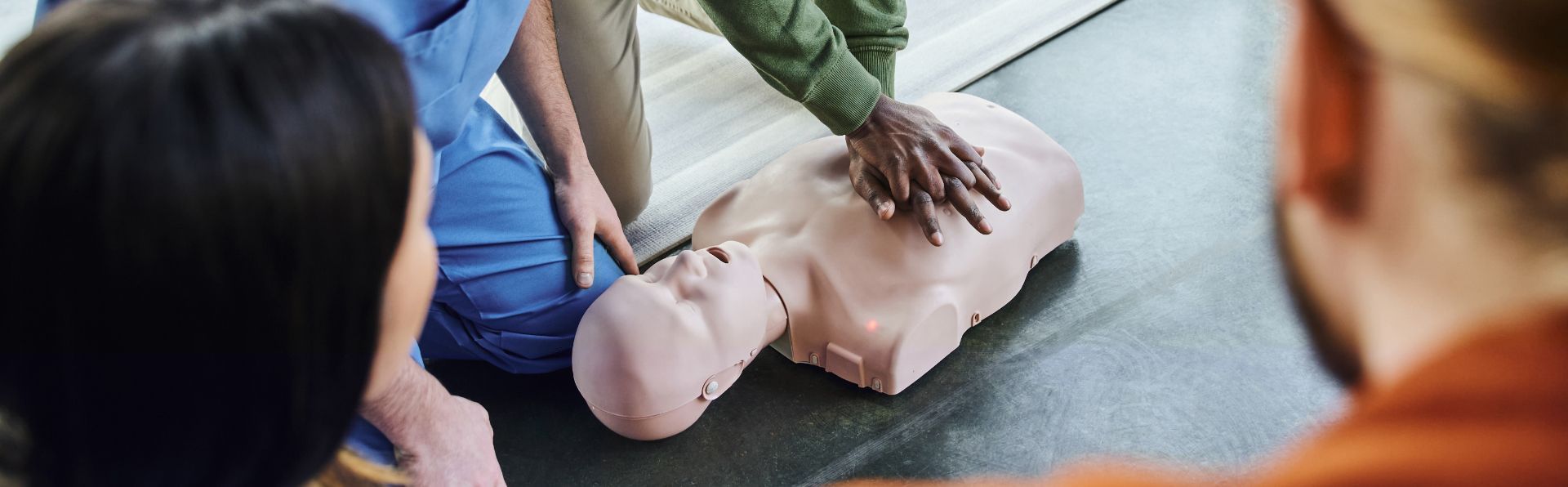 A group of people are practicing first aid on a mannequin.