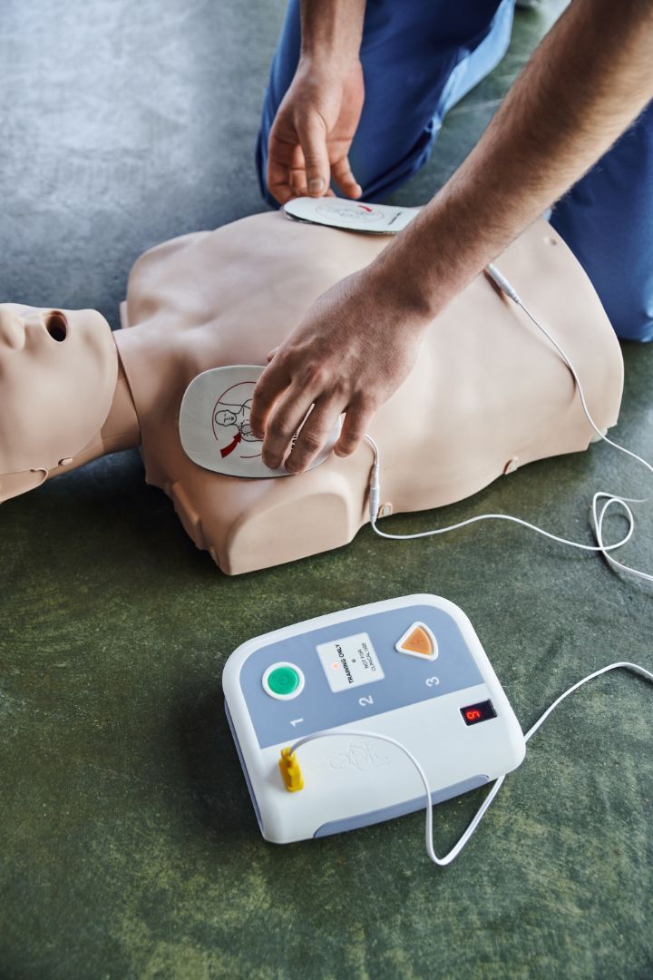 A professional demonstrating CPR on a training manikin during an instructor certification course