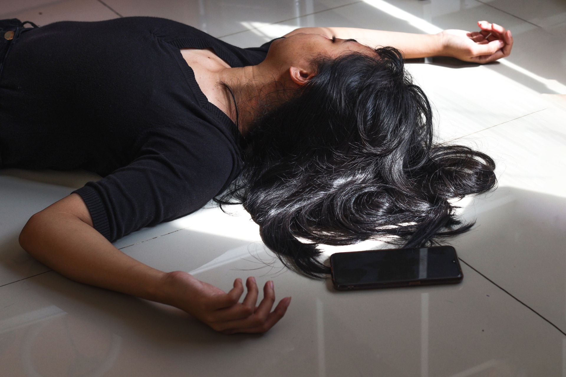 A woman is laying on the floor next to a cell phone.