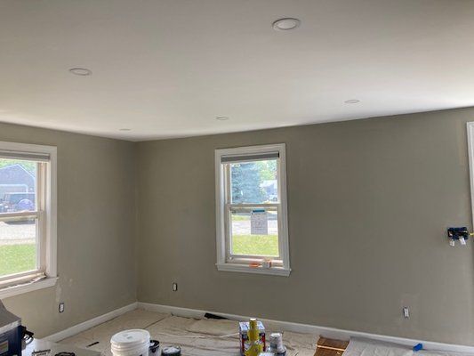 Interior room with painted walls and ceiling, two windows, and recessed lighting.