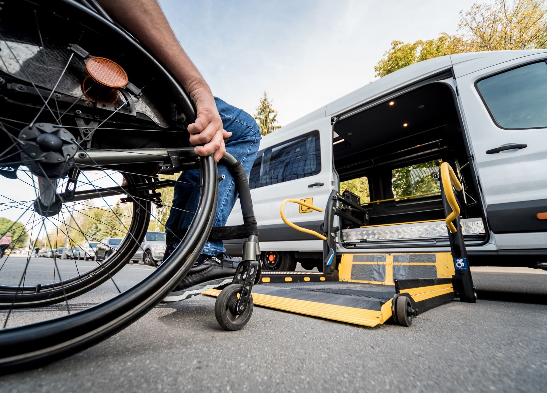 A man in a wheelchair moves to the lift of a specialized vehicle.