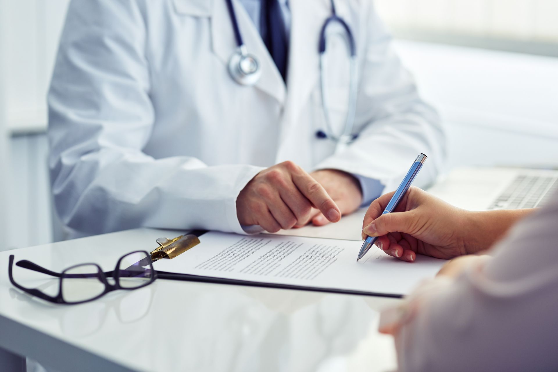 Female patient in office filling out medical document with doctor.