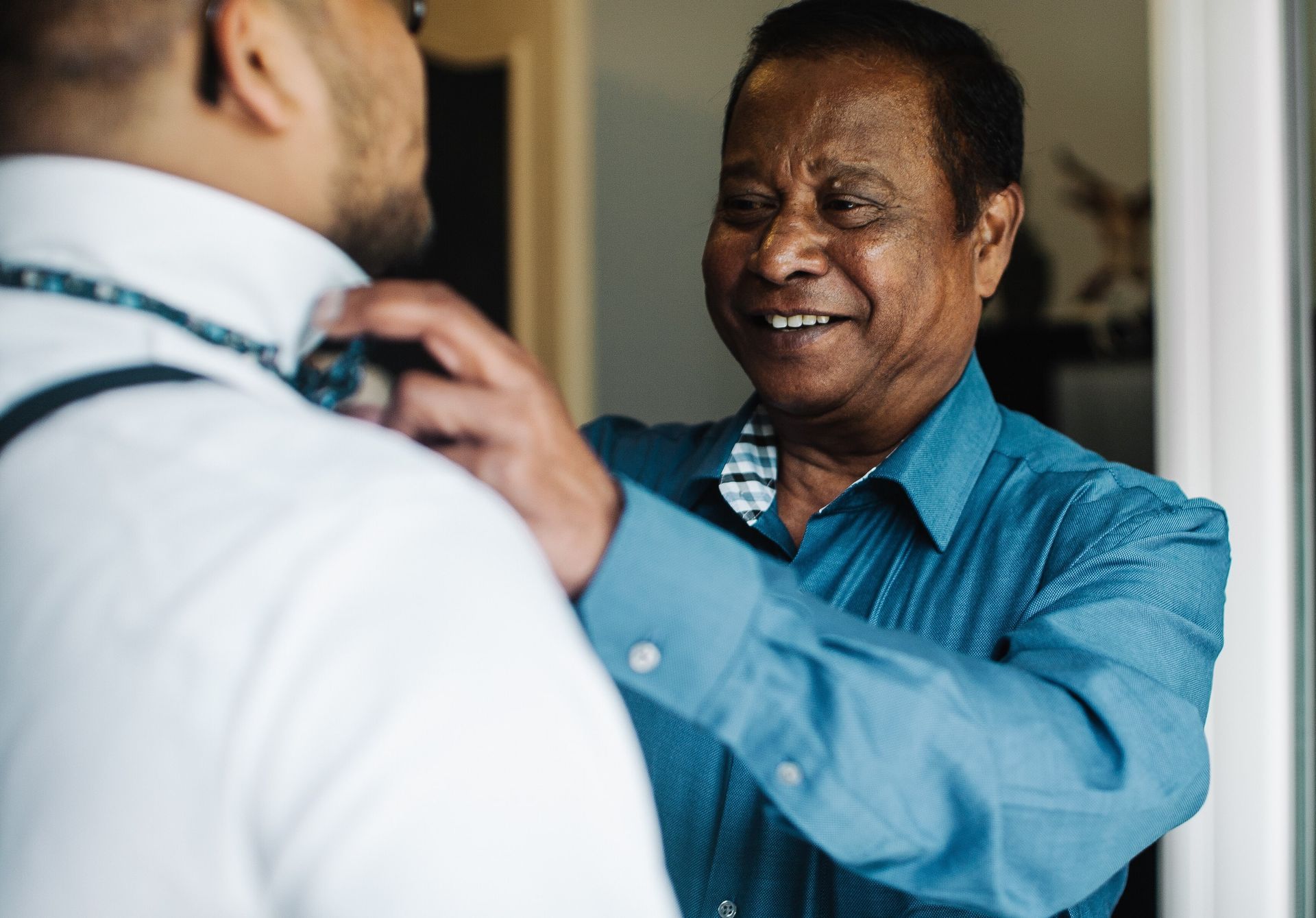 A man is adjusting his tie in front of a mirror.