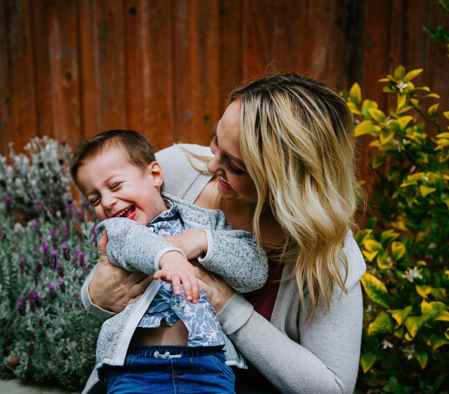 A woman is holding a baby in her arms and the baby is laughing.