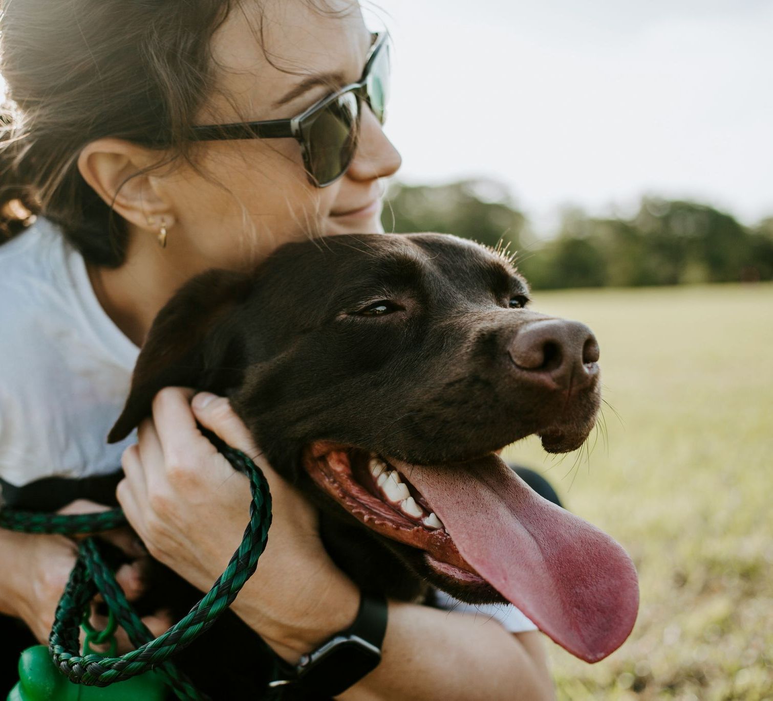 A woman is holding a brown dog with its tongue hanging out