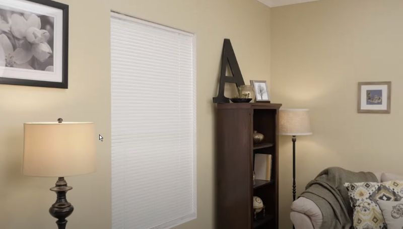 A living room with a couch , lamp , bookshelf and window.