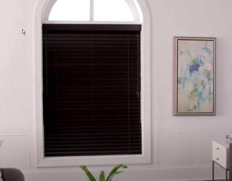 A living room with a window with blinds and a painting on the wall.