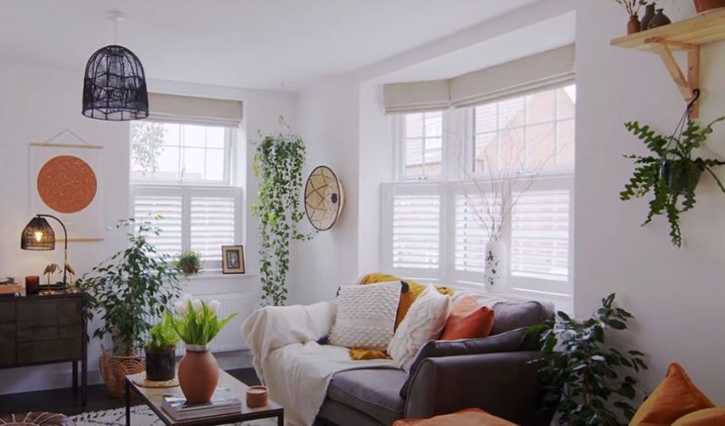 A living room with a couch , chair , table and plants.