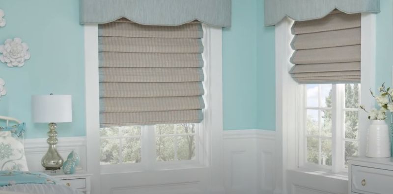 A bedroom with blue walls and roman shades on the windows.