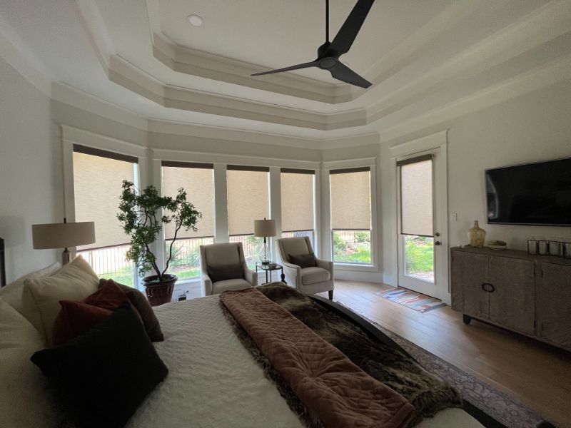 A bedroom with a bed , chairs , a television and a ceiling fan.