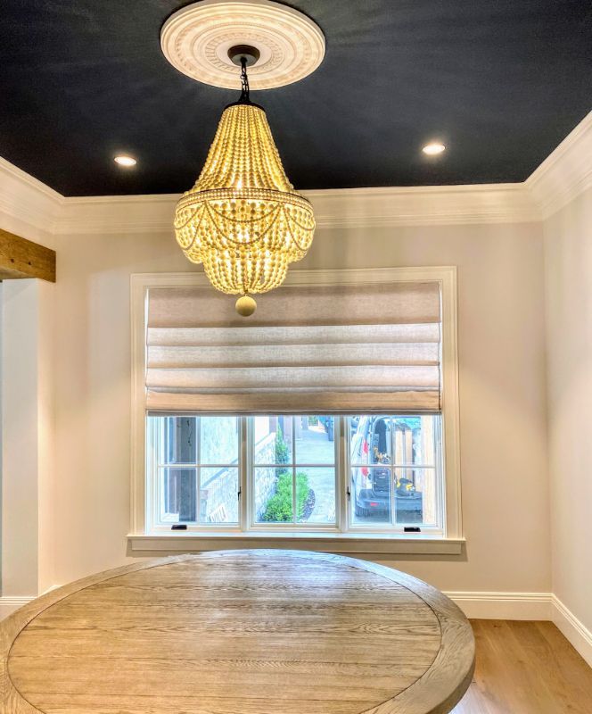 A dining room with a round table and a chandelier hanging from the ceiling.