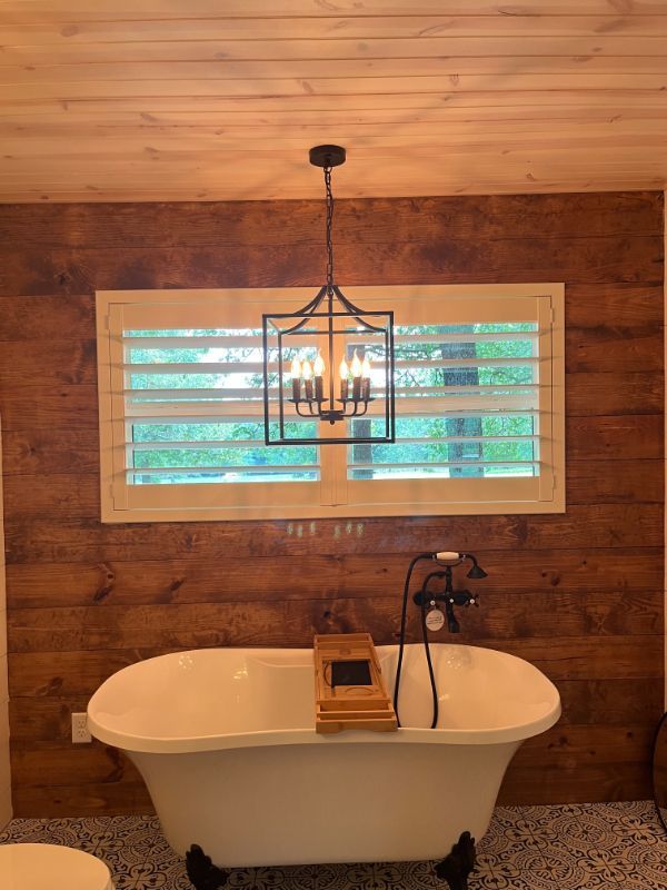 A bathroom with a bathtub and a window with shutters.