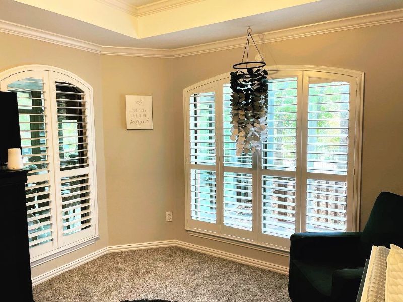 A living room with a couch , chair , and shutters on the windows.