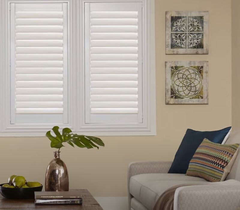 A living room with a couch and shutters on the windows