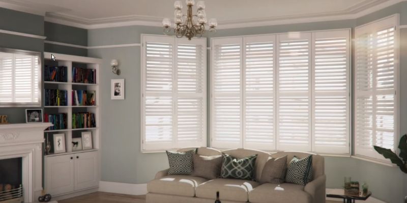 A living room with a couch , fireplace , bookshelf and shutters.