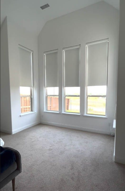 A bedroom with a lot of windows and blinds on them.