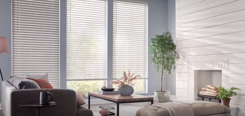 A living room with a couch , coffee table , fireplace and blinds.