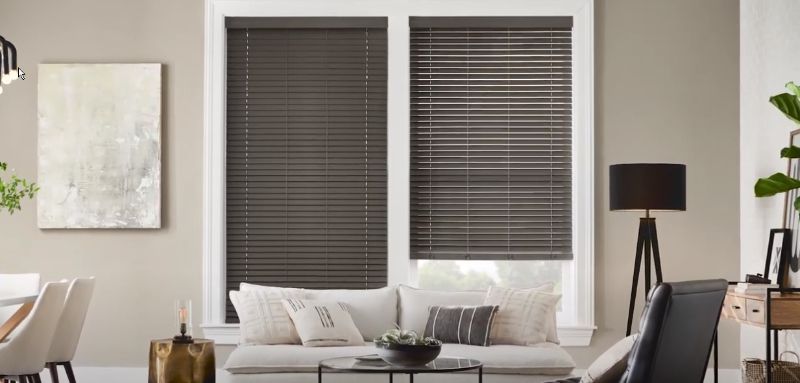 A living room with a couch , chairs , and a window with blinds.