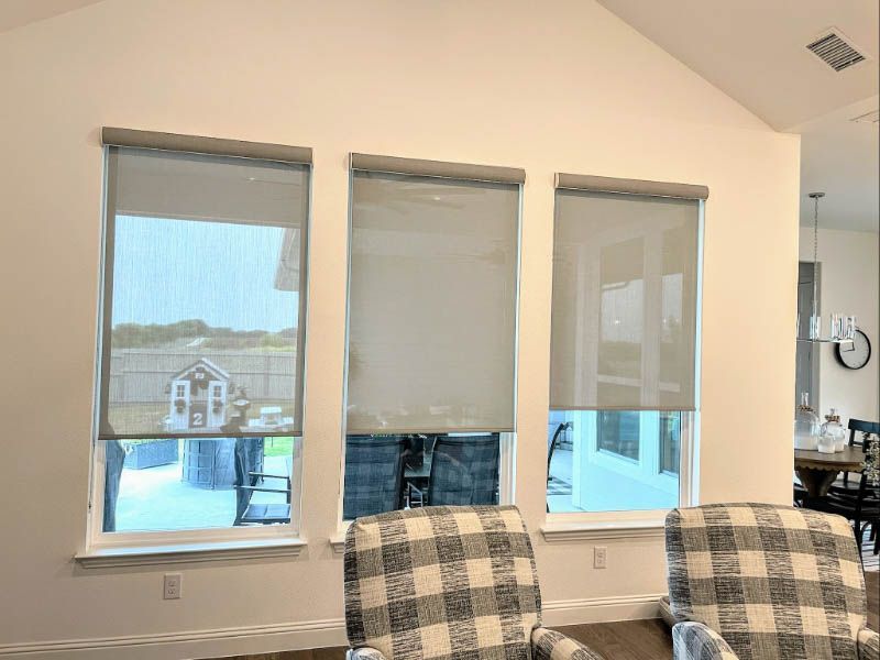 A living room with three windows and three chairs.